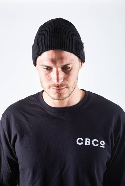 Front view of a man looking downward in a black-colored beanie featuring Billy Bones available at CBCO