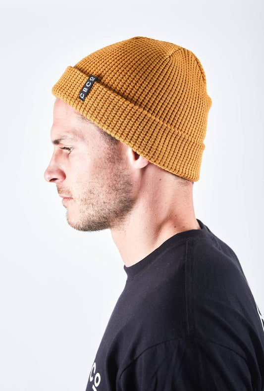Side view of a man in a mustard-colored beanie featuring Billy Bones available at CBCO
