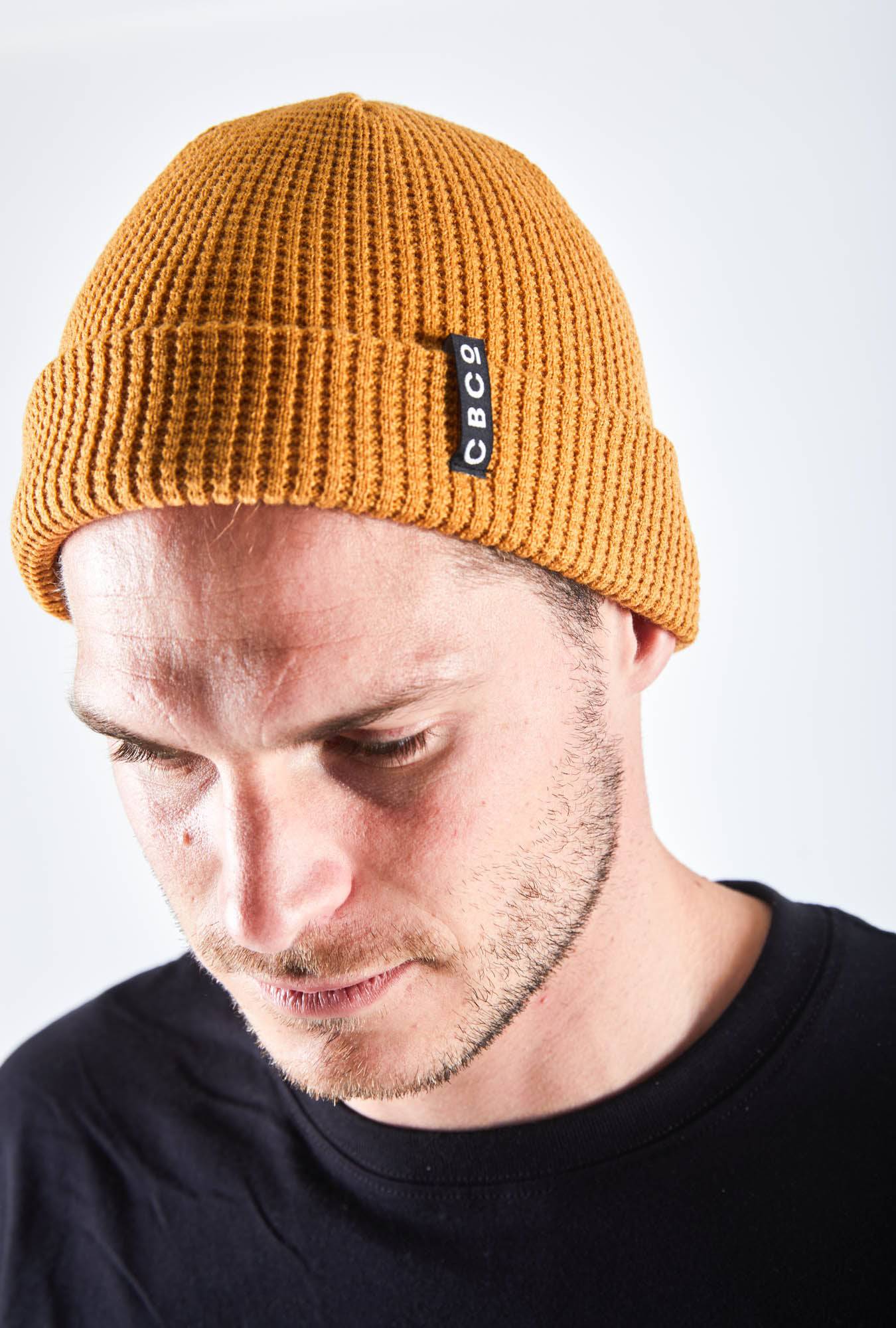 Close-up view of a Man looking downward in mustard beanie with Billy Bones design, available at CBCO