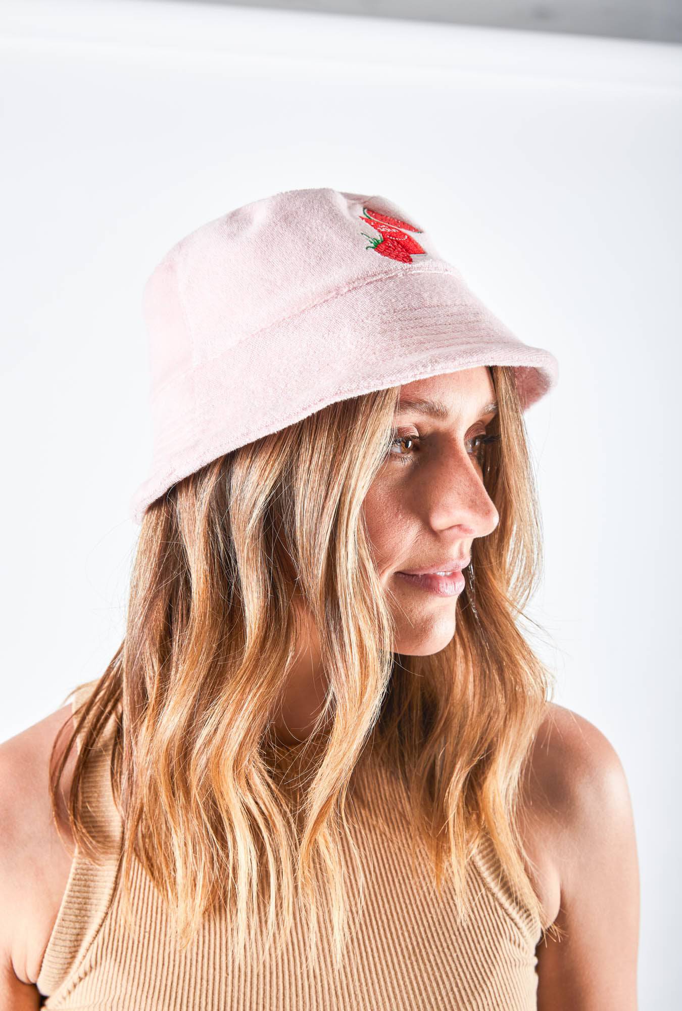 Woman is wearing Colonial Brewing Co, CBCO pink bucket hat with an image of the South West Sour Beer Can, watermelon and strawberries on it.