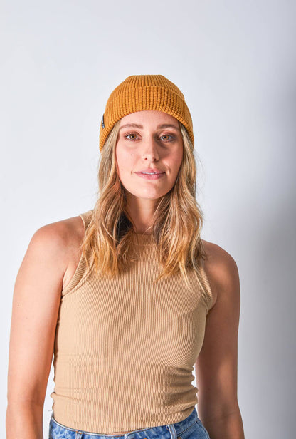 Front view of a woman in a mustard-colored beanie featuring Billy Bones available at CBCO