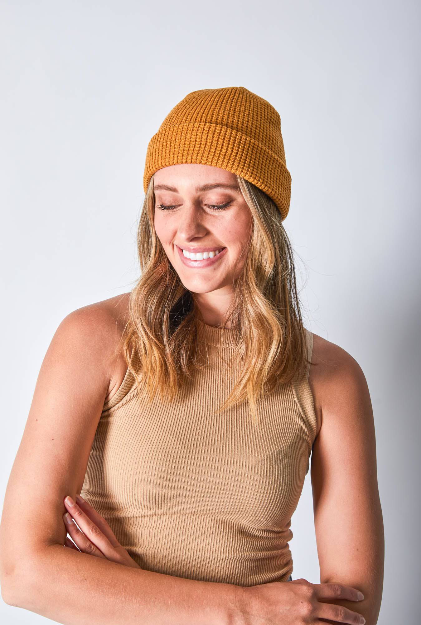 Front view of a woman in a mustard-colored beanie crossing her hands featuring Billy Bones available at CBCO
