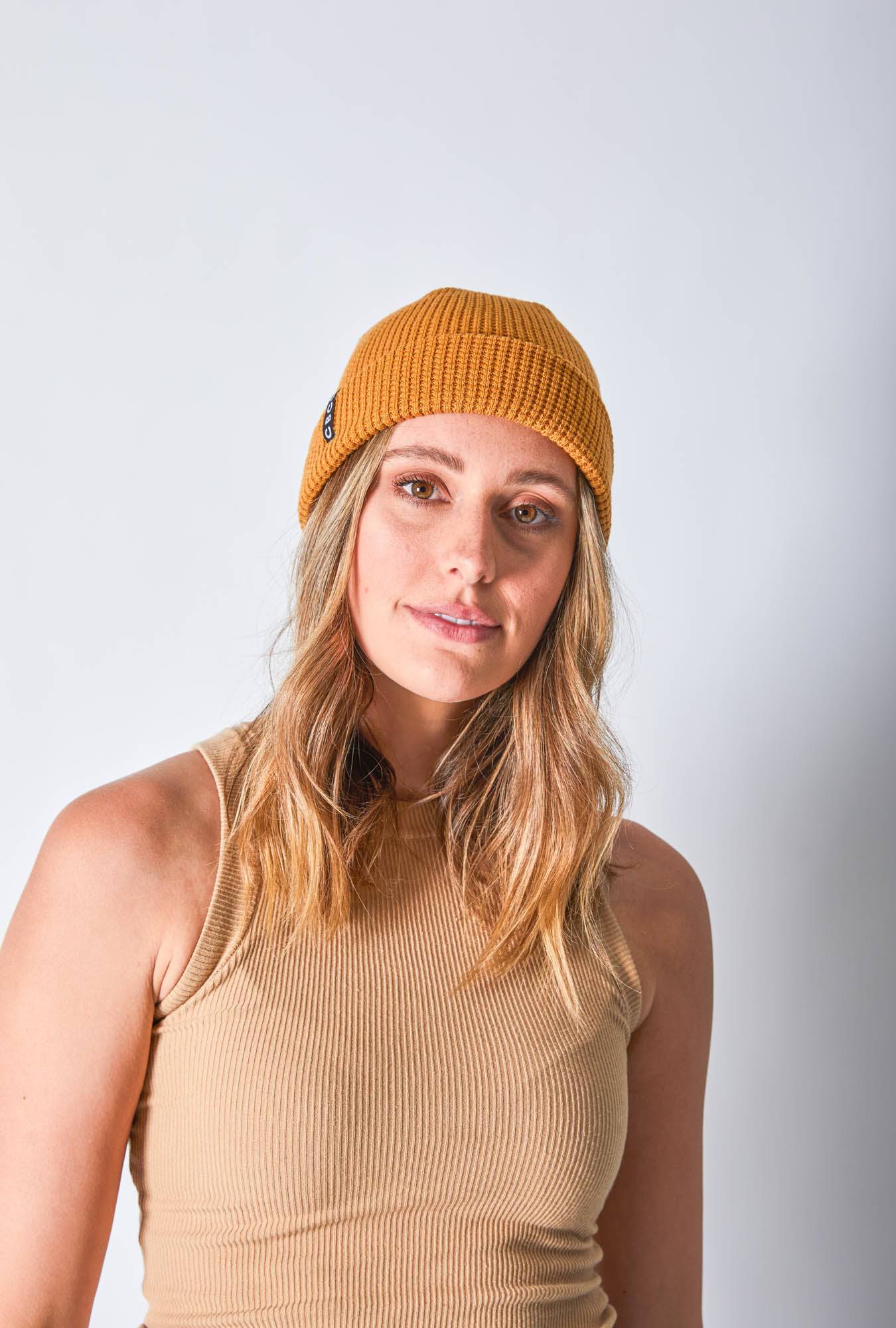 Front view of a woman in a mustard-colored beanie featuring Billy Bones available at CBCO