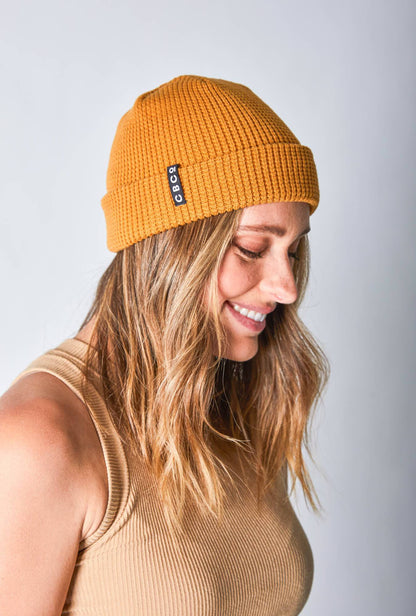 Side view of a woman in a mustard-colored beanie featuring Billy Bones available at CBCO